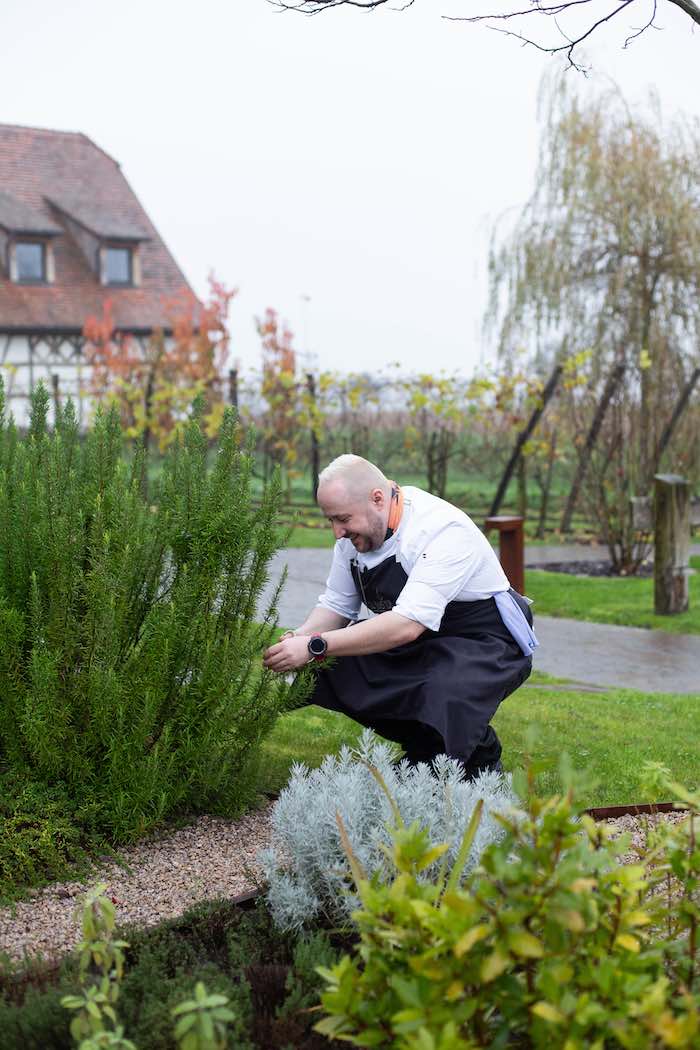 Maxime Ohlmann, le second de cuisine, cueillant des herbes aromatiques dans le jardin. © Christophe Urbain